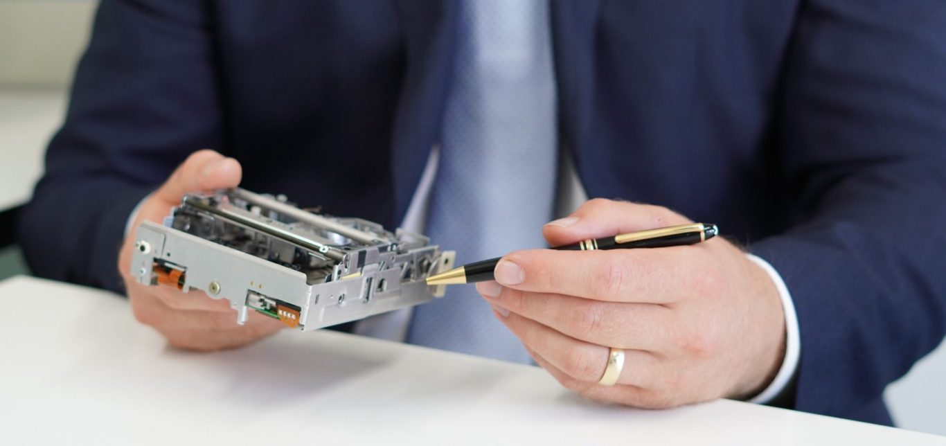 Ein Mann hält ein elektronisches Gerät und benutzt einen Stift, um auf Details hinzudeuten.